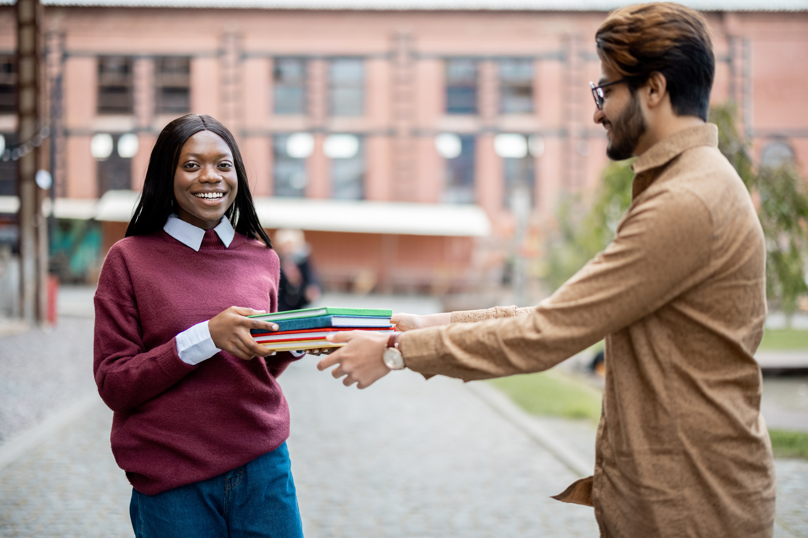 Indian Man Giving Books to Black Girl Outdoors